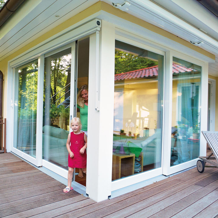 Kind durch offene Schiebeglastuer zur Terrasse