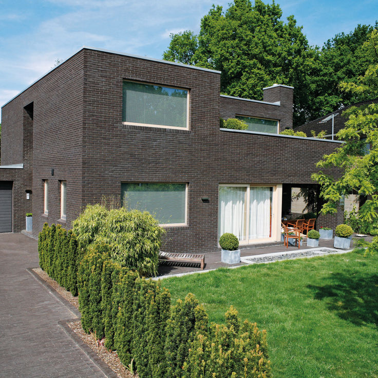 Haus mit Flachdach und dunkler Mauerwerksfassade