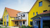 Haeuserverbund mit gelber Fassade und blauen Fenstern