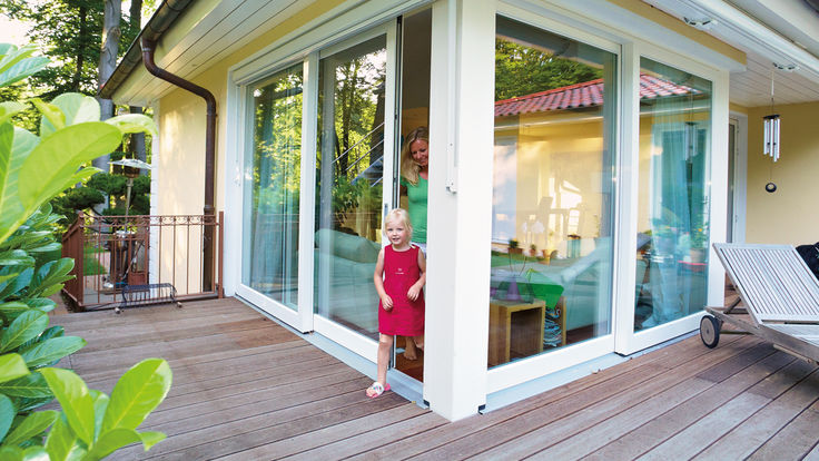 Kind durch offene Schiebeglastuer zur Terrasse