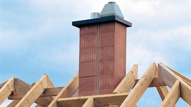 Kamin zwischen Holzsparren eines unfertigen Daches