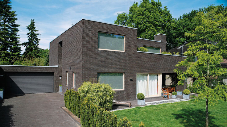 Haus mit Flachdach und dunkler Mauerwerksfassade
