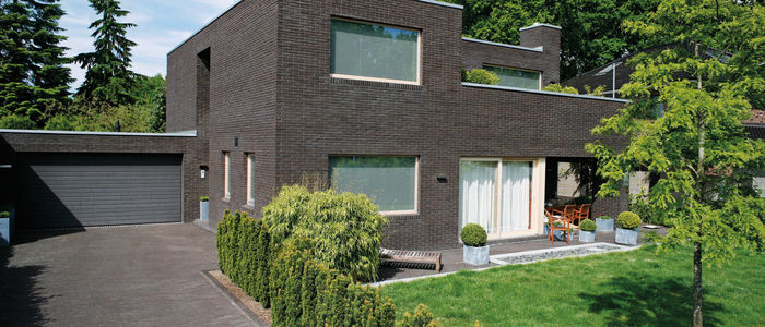 Haus mit Flachdach und dunkler Mauerwerksfassade