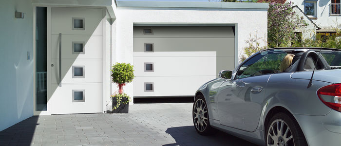 Silbernes Auto vor weißer Garage mit Sectionaltor