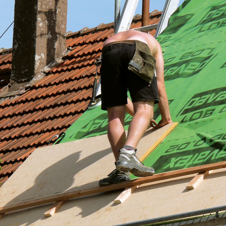 Dachdecker verlegt Holzfaser-Daemmplatte an der Dachschraege